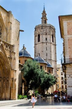 a woman is walking down the street in front of an old building