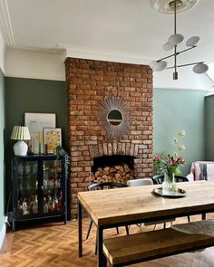 a dining room table with chairs and a fire place in front of a brick fireplace