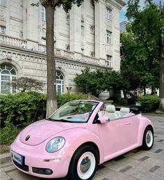 a pink convertible car parked in front of a large building