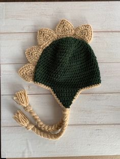 a crocheted green and beige hat on top of a white wooden table next to a string