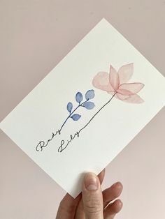 a hand holding up a card with watercolor flowers on it