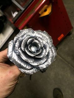 a silver flower is held in someone's hand near a toolbox and other tools