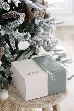 a white box sitting on top of a wooden table next to a christmas tree with decorations