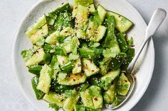 a white bowl filled with cucumber and sesame seeds on top of a table