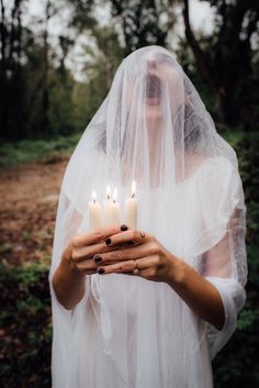 a woman wearing a veil holding candles in her hands