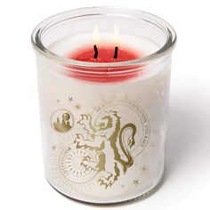 a candle that is sitting inside of a glass container on a white surface with the lid open