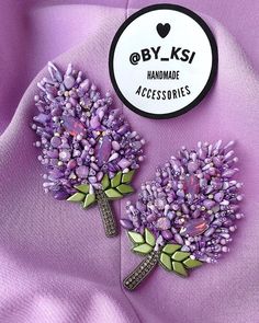 two brooches that are sitting on a purple cloth with the words by ksi