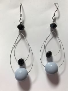 two pairs of earrings with black and white beads hanging from silver hoops on a white surface