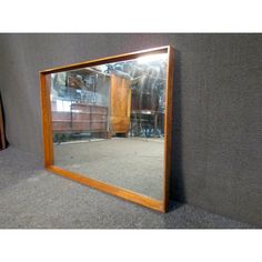 a large mirror sitting on the floor in front of a gray wall and grey carpet