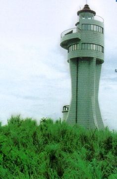 a tall light house sitting on top of a lush green field