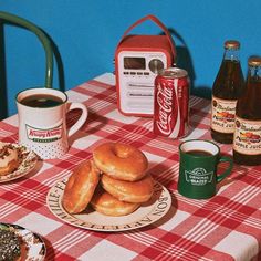 a table topped with donuts next to two cups of coffee and bottles of soda