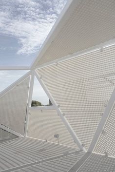 an open area with white walls and flooring under a blue sky filled with wispy clouds