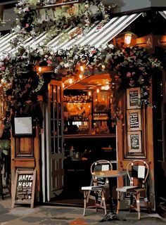 the outside of a restaurant with tables and chairs under an awning that has flowers growing over it