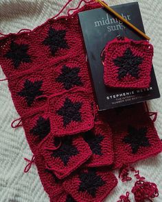 a crocheted blanket and coasters with a book on the table next to it