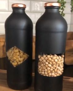 two black bottles filled with food on top of a wooden table