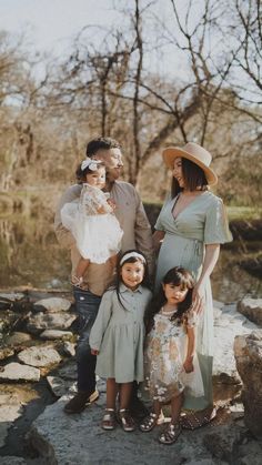 a family posing for a photo in front of some rocks and water with trees behind them