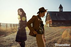 a man and woman standing in front of a barn with the sun shining on them