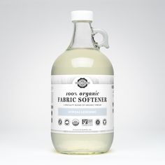 a bottle of organic fabric softener sitting on a white surface with clippings