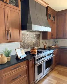 a kitchen with wooden cabinets and stainless steel stove top oven in the center, surrounded by wood flooring