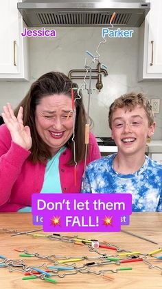 a woman and boy sitting at a kitchen table with magnets on the board that says don't let them fall