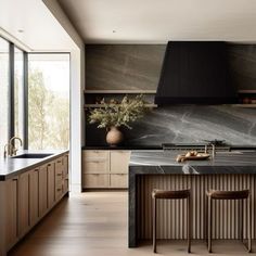 a large kitchen with marble counter tops and wooden cabinets, along with two bar stools