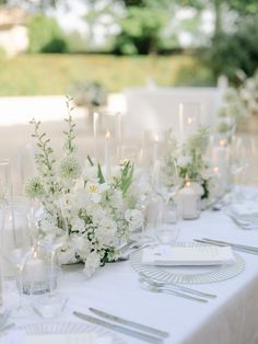 the table is set with white flowers and place settings for guests to sit down at