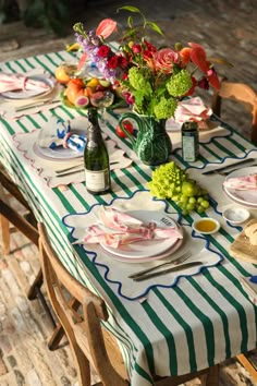 the table is set with plates and flowers in vases on it, along with wine bottles