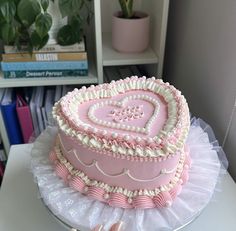 a pink heart shaped cake sitting on top of a table