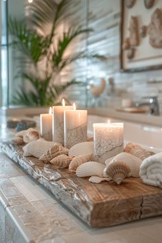 candles and seashells sit on a wooden tray in the middle of a bathroom