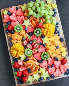 a wooden cutting board topped with cut up fruits and veggies on top of it