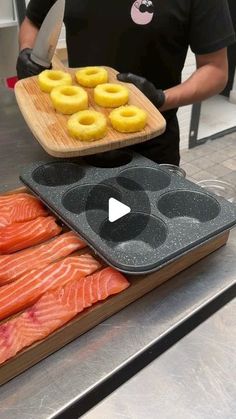 a man holding a tray full of salmon and donuts