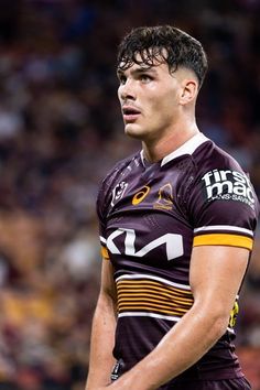 a rugby player is standing on the field with his hands in his pockets and looking off to the side