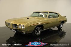 an old muscle car is on display in a showroom with black flooring and white walls