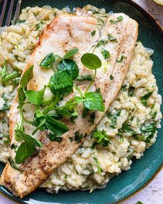 fish and rice on a blue plate with green garnishes next to a fork