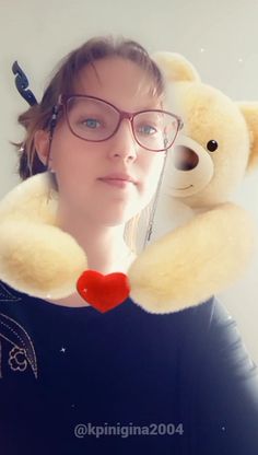 a woman wearing glasses and holding a teddy bear behind her back with a red heart on it's neck