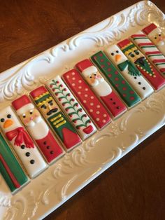 decorated cookies in the shape of santa and snowmen on a white platter with ornate border