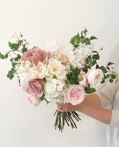 a woman holding a bouquet of white and pink flowers