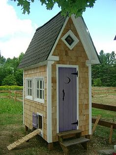 a small wooden house sitting on top of a grass covered field next to a fence