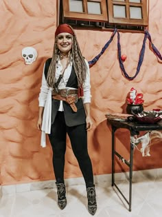 a woman dressed as a pirate standing in front of a wall