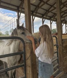 a girl petting a horse in an enclosed area