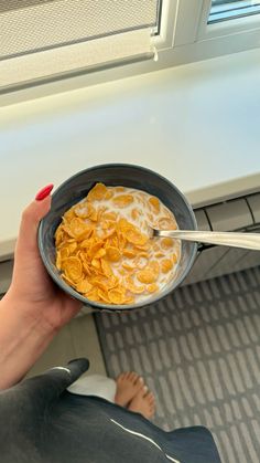 a woman is holding a bowl of cereal