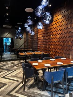 an empty restaurant with blue chairs and wooden tables in front of a wood paneled wall