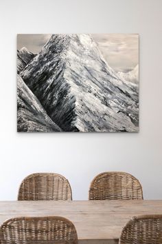 a dining room table with wicker chairs and a painting on the wall above it