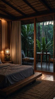 a large bed sitting in a bedroom next to a sliding glass door that looks out onto the jungle