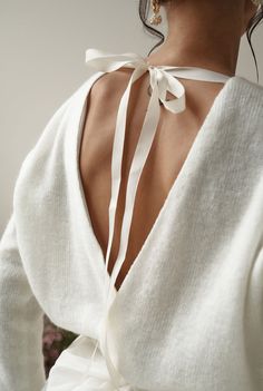 the back of a woman's sweater with a white ribbon on her neck and shoulders