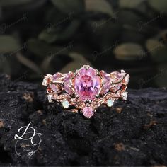 a pink diamond ring sitting on top of a rock