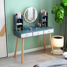 a blue and white desk with a mirror on it next to a potted plant