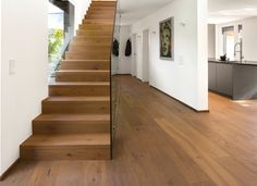 there is a wooden stair case in this modern house with white walls and wood floors