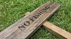 a wooden sign that says no fishing on it sitting in the grass next to some wood planks