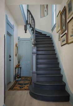 a staircase leading up to the second floor in a house with blue doors and framed pictures on the wall